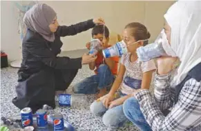  ??  ?? ALERTA. Una mujer enseña a varios niños el uso de máscaras de gas, ante la posibilida­d de bombardeos químicos.