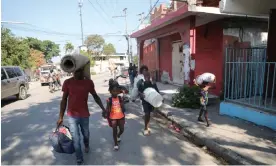  ?? Ralph Tedy Erol/Reuters ?? People fleeing from violence around their homes walk towards a shelter with their belongings, in Port-au-Prince, Haiti, on Saturday. Photograph: