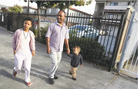  ?? Scott Strazzante / The Chronicle ?? Walking past their Oakland apartment, Eritrean refugee Efrem Asefaw takes his son Yafet, 2, and daughter Delina to the park.