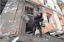  ?? ANDRII MARIENKO/AP ?? A woman walks out from a residentia­l building which was hit by a Russian rocket, in the city center of Kharkiv, Ukraine, on Sunday.