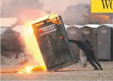  ?? CHRISTOPHE­R FURLONG / GETTY IMAGES ?? A migrant tries to push over a toilet Monday as French authoritie­s began the complex operation of shutting down the makeshift migrant camp in Calais. Authoritie­s say the camp holds nearly 6,500 people who are trying to get to the U.K.