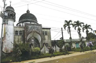  ?? — AFP ?? MARAWI: Philippine Marines walk past a mosque during a patrol along a deserted street at the frontline.