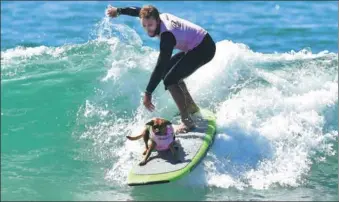  ?? FREDERIC J. BROWN / AGENCE FRANCE-PRESSE ?? A surfer rides a wave with surf dog Giselle during the 10th annual Surf City Surf Dog contest in Huntington Beach, California, on Saturday.