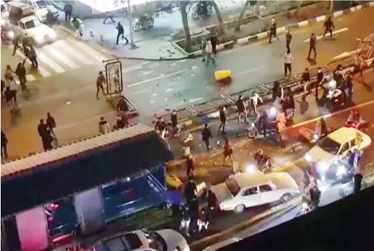  ??  ?? An image grab taken from a handout video released by Iran’s Mehr News agency reportedly shows a group of men pushing traffic barriers in a street in Tehran on Dec. 30. (AFP)