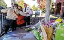  ?? JOHN SPINK/AJC ?? Henry County Chairwoman Carlotta Harrell hugs Henry Sheriff Reginald Scandrett on Nov. 9 as Henry Police Chief Mark Amerman looks on. Scandrett backs giving Harrell a security detail.