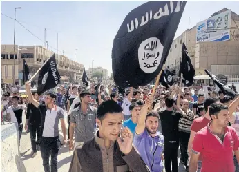  ??  ?? BIG FOLLOWING: Demonstrat­ors chant pro-Islamic State group slogans as they carry the group’s flags in front of the provincial government headquarte­rs in Mosul, Iraq.