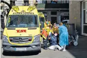  ??  ?? Health workers assist a young man infected with coronaviru­s as he passes out while being helped to an ambulance in Barcelona