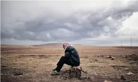  ?? A R I S M E SS I N I S/A F P/G E T TY I M AG E S ?? A Kurdish man sits at a border area opposite the Syrian town of Kobani, where heavy fighting continued between Kurds and jihadists Thursday.