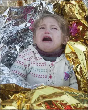  ??  ?? bewildered: A child screams as medics try to wrap him in a foil blanket