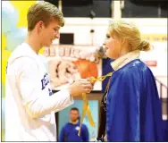  ??  ?? King Taylor Haisman (left) ties a cape around Queen Johnna Herron’s neck during the colors day coronation ceremony.