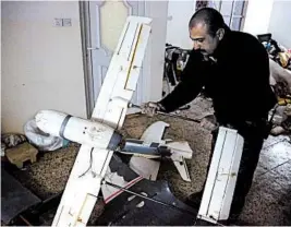  ?? KHALID MOHAMMED/AP ?? An Iraqi officer inspects drones seized from an Islamic State warehouse where militants modified them for war.