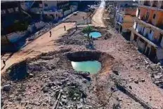  ?? Reuters ?? A drone footage shows people standing near craters and damaged buildings in a rebel-held area of Aleppo.