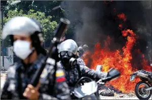  ?? AP/ARIANA CUBILLOS ?? Venezuelan national police move away from the flames after an explosion at Altamira Square during clashes with anti-government demonstrat­ors Sunday in Caracas, Venezuela.