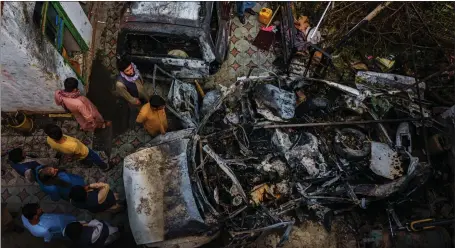  ??  ?? Afghans gather around the incinerate­d remains of a vehicle targeted and destroyed by an American drone strike in Kabul