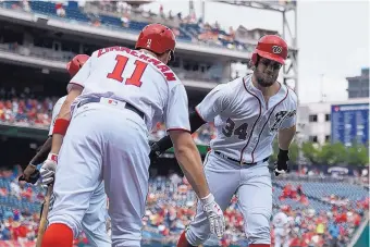  ?? NICK WASS/ASSOCIATED PRESS ?? Washington’s Bryce Harper (34) celebrates his two-run homer in the first inning with Ryan Zimmerman on Thursday. The Nationals hit eight homers and won 15-2.
