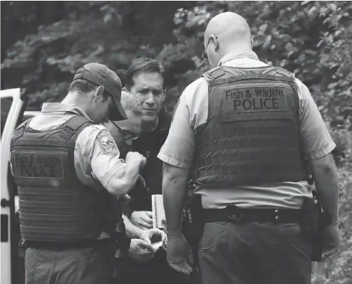  ?? ALAN BERNER / THE SEATTLE TIMES VIA THE ASSOCIATED PRESS ?? Washington state Fish and Wildlife police confer with an individual from the King County medical examiner’s and a King County Sheriff ’s deputy on a remote gravel road above Snoqualmie, Wash., following a fatal cougar attack on Saturday.