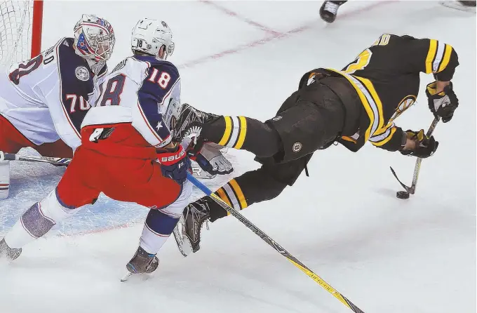  ?? STAFF PHOTO BY MATT WEST ?? FLY GUY: Brad Marchand tries to get off a shot in overtime after being tripped up by Blue Jackets center Pierre-Luc Dubois last night at the Garden.