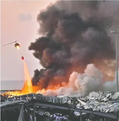  ?? STR / AFP VIA GETTY IMAGES ?? A helicopter assists in firefighti­ng efforts at the scene of Tuesday’s deadly blast in the Lebanese capital of Beirut. Prime Minister Hassan Diab said on Tuesday that those responsibl­e for the explosion will be held accountabl­e.