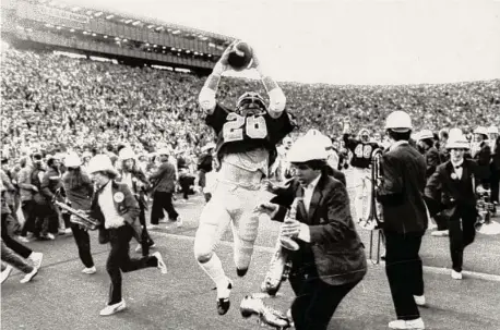  ?? Robert Stinnett / Associated Press 1982 ?? Cal’s Kevin Moen leaps after scoring the winning touchdown before plowing into Stanford trombonist Gary Tyrrell (not pictured).