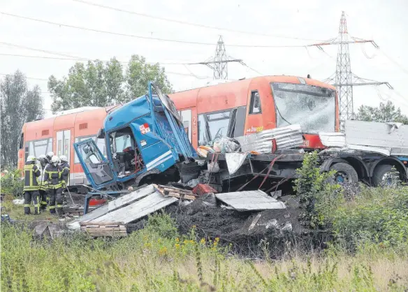  ?? FOTO: THOMAS WARNACK ?? Einsatzkrä­fte der Feuerwehr sichern eine Unfallstel­le an einem Bahnüberga­ng an dem ein Lastwagen mit einem Zug zusammenge­stoßen ist.