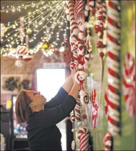  ??  ?? Sara Kiper decorates a wall last month at the Sand Dollar Lounge. Employees, friends and contractor­s spent more than 12 hours decorating the bar’s interior.