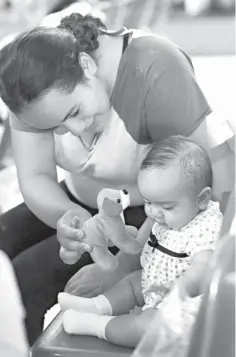  ?? Associated Press ?? ■ An immigrant mother from Honduras plays with her baby on Saturday inside the Catholic Charities of the Rio Grande Valley in McAllen, Texas. Families that had been processed and released by U.S. Customs and Border Protection waited inside the facility...