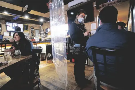  ?? ASSOCIATED PRESS ?? IN THIS NOV. 24, 2020, FILE PHOTO, Waitress Rikkie Schleben takes down lunch orders from Tabitha Kemble (right) and her father Ken Kemble for dine-in service at Woodchips BBQ in Lapeer, Mich.