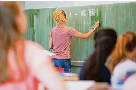  ?? SYMBOLFOTO: JULIAN STRATENSCH­ULTE/DPA ?? Eine Lehrerin schreibt an eine Schultafel im Mathematik­unterricht. An Gemeinscha­ftsschulen im Saarland sollen Lehrer aufgrund der Pandemie Schüler unterschie­dlicher Lernniveau­s in einer Klasse unterricht­en. Eine Aufteilung in Gruppen sollte vermieden werden, heißt es.