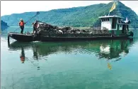  ?? RAO GUOJUN / FOR CHINA DAILY ?? Workers remove floating objects from the Xiaojiang River, a tributary of the Yangtze River, in Chongqing in October.