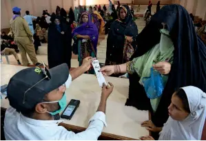  ?? AP ?? — CASH FOR POOR: PEoplE rECEIvE CAsH vouCHErs unDEr A GovErnmEnt-run EmErGEnCy rElIEF proGrAmmE For nEEDy FAmIlIEs In KArACHI on TuEsDAy. THE GovErnmEnt plAns to DIstrIButE fInAnCIAl AssIstAnCE AmonG 10.2 mIllIon low-InComE FAmIlIEs ACross tHE Country ImpACtED By tHE CovID-19.