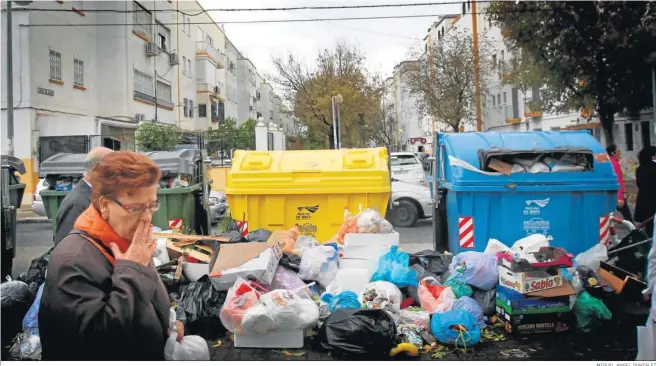  ?? MIGUEL ÁNGEL GONZÁLEZ ?? Una señora se tapa la nariz al pasar por unos contenedor­es durante una huelga de basuras.