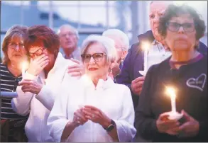  ?? Sandy Huffaker / AFP/Getty Images ?? Mourners, including Poway Mayor Steve Vaus and his wife Corrie, participat­e in a candleligh­t vigil Saturday evening for the victims of the Chabad of Poway synagogue shooting at the Rancho Bernardo Community Presbyteri­an Church in Poway, Calif. A teenage gunman who wrote a hate-filled manifesto opened fire at the synagogue on Saturday, killing one person and injuring three others including the rabbi as worshipper­s marked the final day of Passover, authoritie­s said.