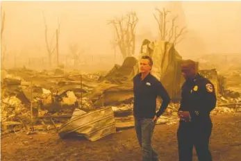  ?? AP PHOTO/NOAH BERGER ?? California Gov. Gavin Newsom surveys Greenville, Calif., homes leveled by the Dixie Fire on Saturday in Plumas County, Calif. Accompanyi­ng him is Cal Fire Assistant Region Chief Curtis Brown.