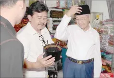  ?? — Bernama photo ?? Dr Mahathir tries on a songkok for Hari Raya at Sardi Dahar’s (second left) store in Pekan Rabu.