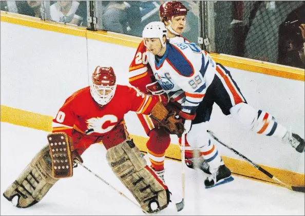  ?? — EDMONTON SUN ?? Edmonton’s Wayne Gretzky gets hit by Calgary’s Gary Suter behind goalie Mike Vernon at the height of the rivalry in the ’80s.