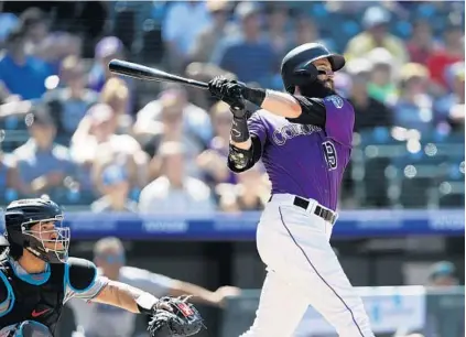  ?? DAVID ZALUBOWSKI/AP ?? The Rockies’ Charlie Blackmon, right, follows the flight of his solo home run off Marlins starting pitcher Jordan Yamamoto in the sixth inning of Sunday’s game in Denver.