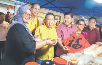  ?? ?? A trader presents her items to Dr Sim during the Deputy Premier’s tour around the CNY 2024 Market at Kenyalang Park.