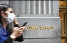  ?? MARK LENNIHAN — THE ASSOCIATED PRESS ?? A woman wearing a mask passes a sign for Wall Street, Tuesday, June 30, 2020, during the coronaviru­s pandemic.