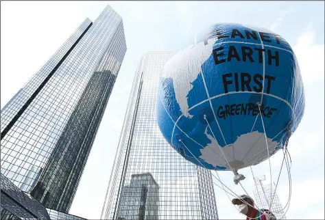  ?? (AP/dpa/Arne Dedert) ?? A demonstrat­or holds a balloon with the words “Planet Earth First” on Friday at the Fridays for Future central climate strike in Frankfurt, Germany, with Deutsche Bank headquarte­rs in background.