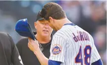  ?? AP-Yonhap ?? Third base umpire Ron Kulpa, left, looks inside the cap of New York Mets’ Jacob deGrom (48) after deGrom pitched in the top of the fifth inning of an MLB game against the Atlanta Braves in New York, Monday.