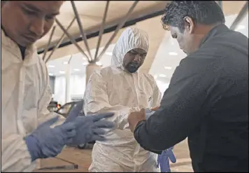  ?? RAHMAN ROSLAN / GETTY IMAGES ?? Members of Atomic Energy Licensing Board put up their Hazmat suit outside the KLIA2 terminal on Sunday in Malaysia. They are investigat­ing the toxic nerve agent death of the estranged half brother of North Korea’s leader.