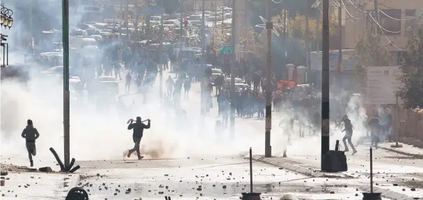  ??  ?? Palestinia­n protesters run for cover from tear gas fired by Israeli troops during clashes at a protest against Trump’s decision to recognize Jerusalem as the capital of Israel, in the West Bank city of Bethlehem. — Reuters photo