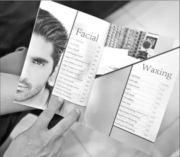  ??  ?? A Pakistani customer checking a price list for services at a men’s salon in Islamabad.