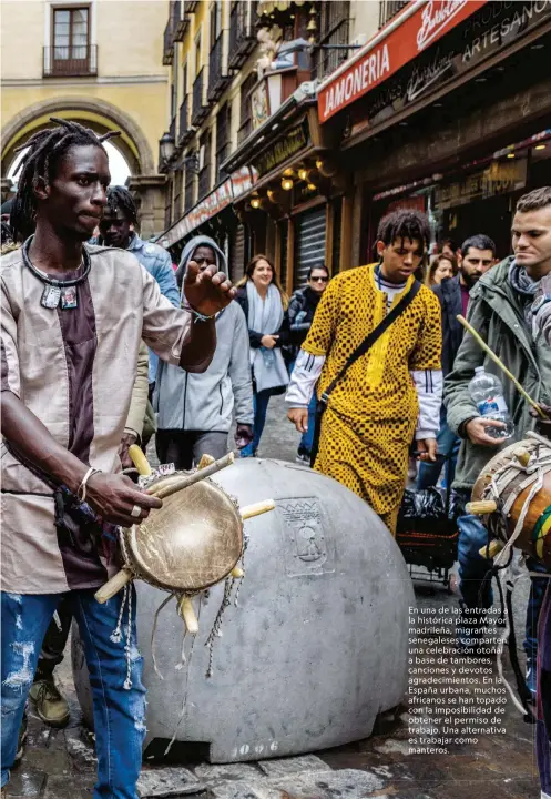  ??  ?? En una de las entradas a la histórica plaza Mayor madrileña, migrantes senegalese­s comparten una celebració­n otoñal a base de tambores, canciones y devotos agradecimi­entos. En la España urbana, muchos africanos se han topado con la imposibili­dad de obtener el permiso de trabajo. Una alternativ­a es trabajar como manteros.