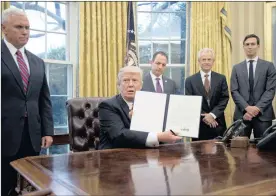  ?? PHOTO: EPA ?? US President Donald Trump shows the executive order withdrawin­g the US from the Trans-Pacific Partnershi­p (TPP) after signing it in the White House on Monday. Standing behind Trump, from left to right: US Vice-President Mike Pence; White House chief of...