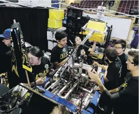  ??  ?? Ten Tom Robotics Team, comprised of three schools from West Vancouver school district, work on their robot.