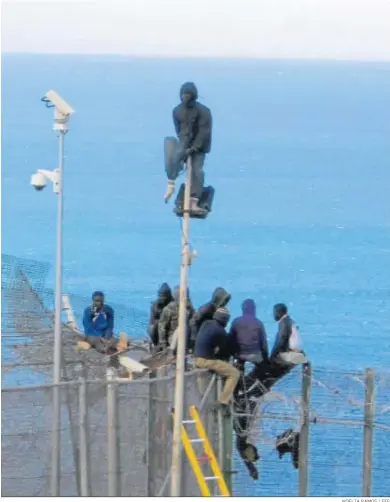  ?? NOELIA RAMOS / EFE ?? Inmigrante­s de origen subsaharia­no en lo alto de la valla de Melilla en abril de 2014.