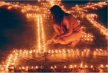  ??  ?? A sadhu painstakin­gly lights up every one of the innumerabl­e earthen lamps on the evening of Dev Deepavali