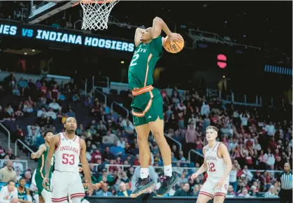  ?? JOHN MINCHILLO/AP ?? Miami’s Isaiah Wong dunks as Indiana’s Tamar Bates, left, and Miller Kopp look on during the second half of the Hurricanes’ victory Sunday in Albany, New York.