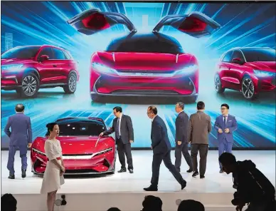  ?? NG HAN GUAN AP FILE PHOTO ?? Attendees take a close look at cars from BYD at the Auto Shanghai 2019 show in Shanghai. China’s auto sales plunged 81.7% in February, 2020, from a year ago after Beijing shut down much of the economy to fight a virus outbreak, adding to problems for an industry that already was struggling with shrinking demand.